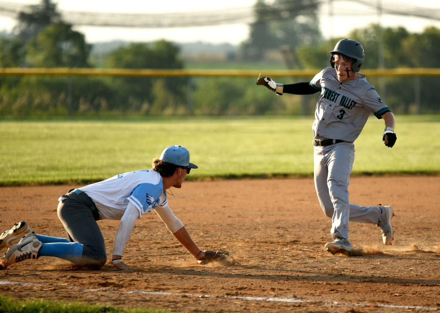Southwest Valley senior Isaac Currin runs to third while East Union third basemanFischer Buffington dives for the ball.