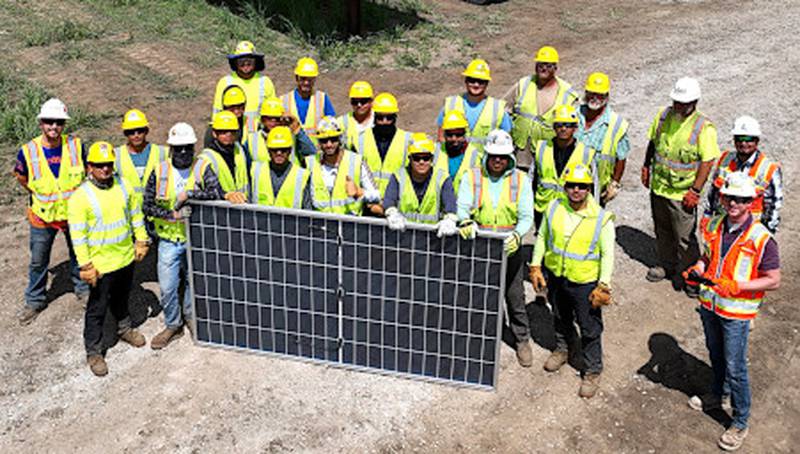Construction crews pose with the last solar panel before it's installed at the Creston site. The solar power project is on schedule to be completed later this year.