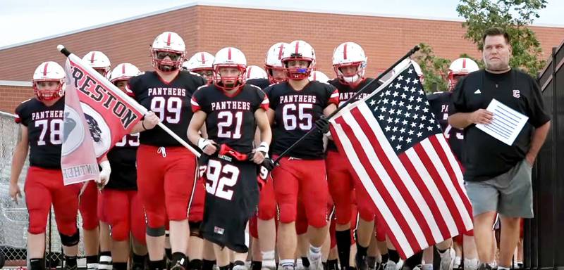 The Creston football team enters the stadium with Coach Brian Morrison prior to a game. Lincoln Keeler (No.21) holds the No. 92 jersey, the number of their late classmate and football teammate, Sterling Sharp, who passed away in 2018. This season has been dedicated to “the 12th man,” referring not only to Sterling, but to everyone they are playing for.