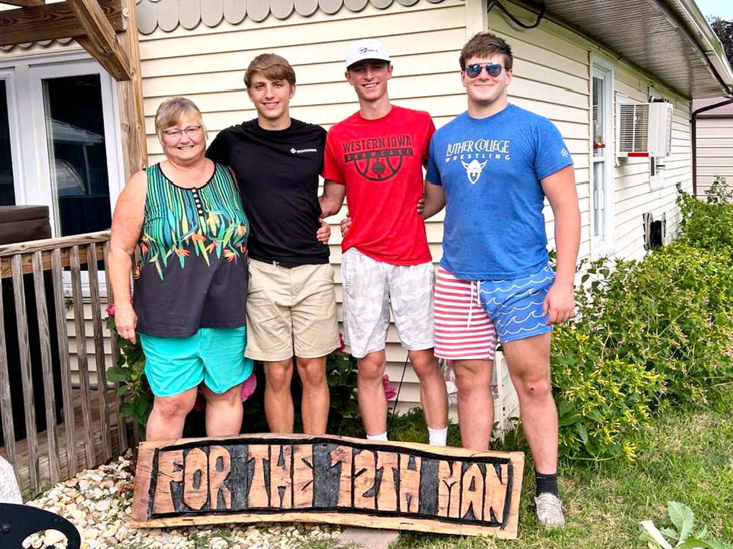 Beth Fry, the grandma of the late Sterling Sharp, is presented with a handmade sign by Creston football seniors Brennan Hayes, Cael Turner and Max Chapman. The team has dedicated this season “to the 12th man.”