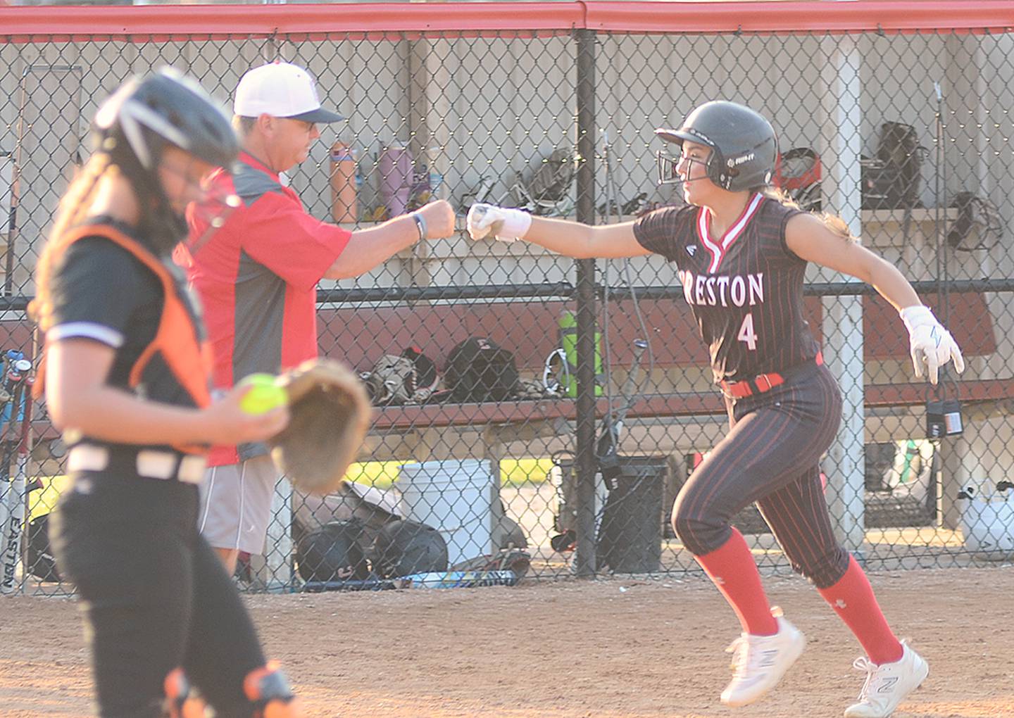 Creston coach Dave Hartman gives Jersey Foote (4) a fist bump after Foote's two-run home run in the seventh inning Monday. Foote had three RBIs in the 12-4 loss.