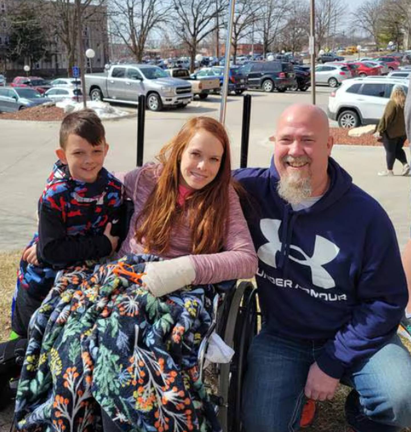 Brysen and Kuri Bolger, two survivors from a 2022 tornado in Winterset, smile with Gymer outside the hospital. Gymer was the 911 dispatcher on the phone with Kuri until first responders arrived.