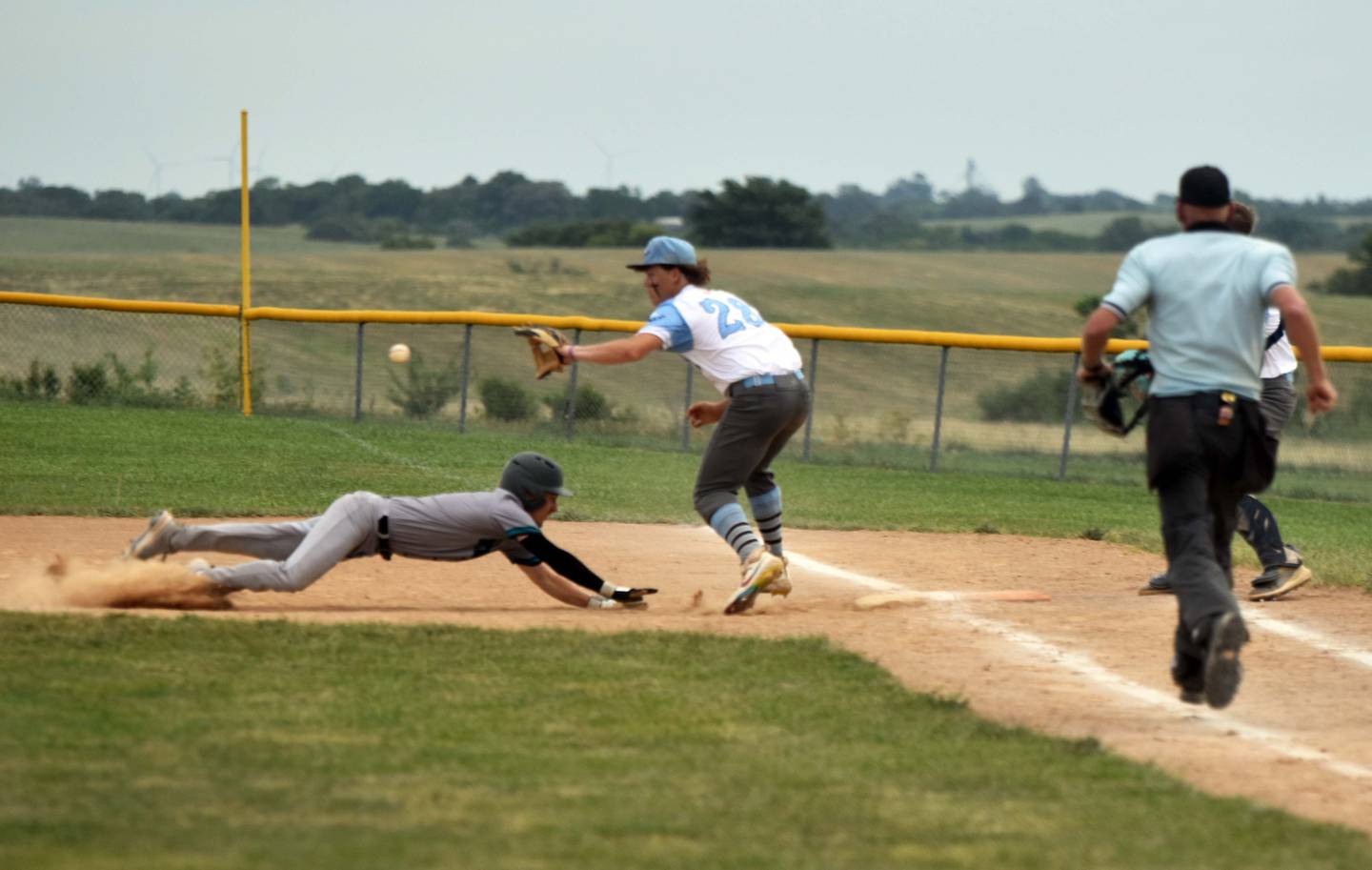 Isaac Currin of Southwest Valley dives back to tag as he was caught in a pickle between first and second base. East Union pitcher Terrian Islas covers first base.