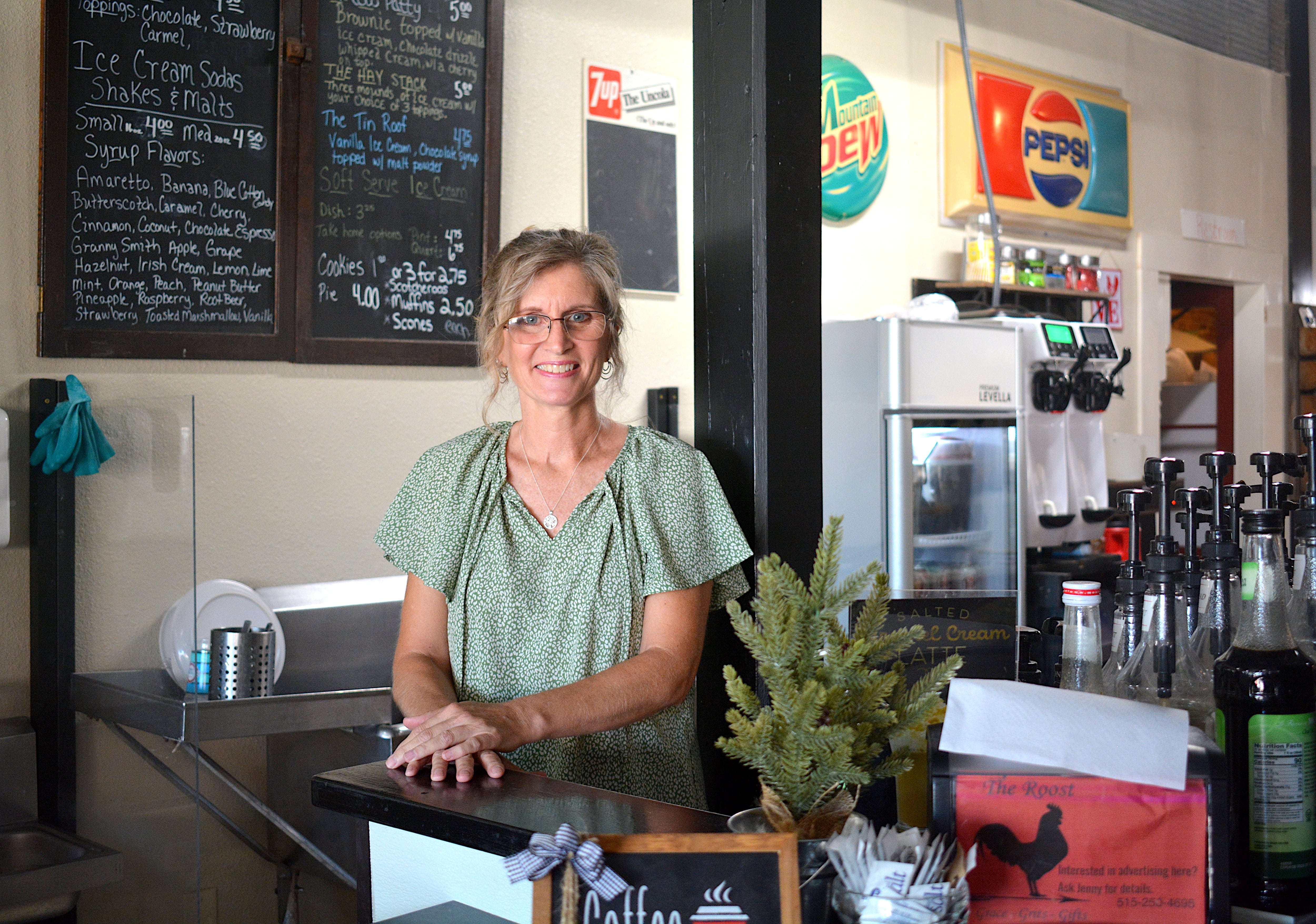 Jennifer Seales owns and operates The Roost, as well as the nearby Jennifer Seales Salon & Boutique and the upstairs Airbnb The Loft. She stands at the coffee bar, along with various antiques showing the history of the building.