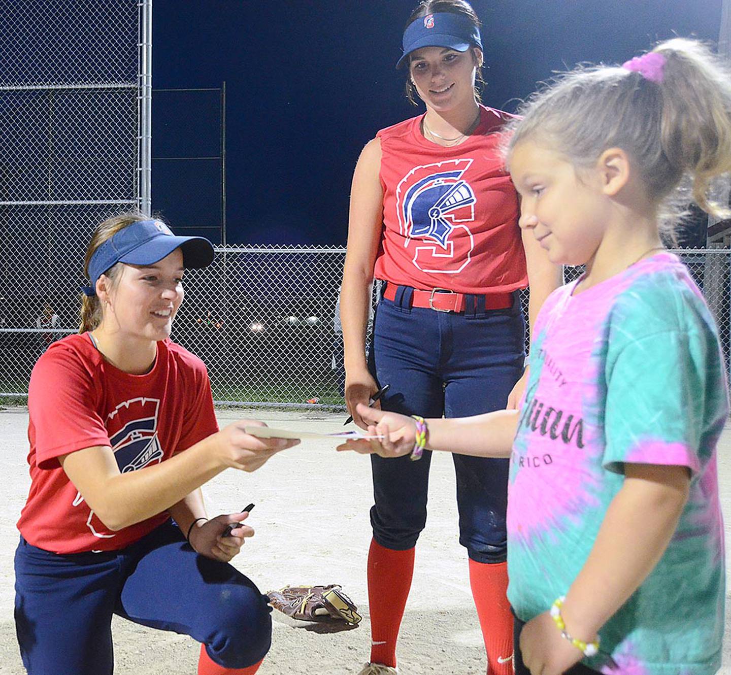 Camp participant Ellie Sick gets an autograph from Southwestern player Jayda Chew of Murray after Monday's camp at the lighted Murray Little League field.