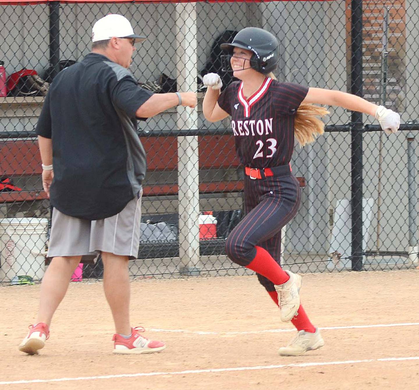 Creston's Avery Staver looks to her teammates at home plate after getting a fist bump from coach Dave Hartman for hitting a home run in the second inning Thursday. Staver had three hits in the 11-1 victory.
